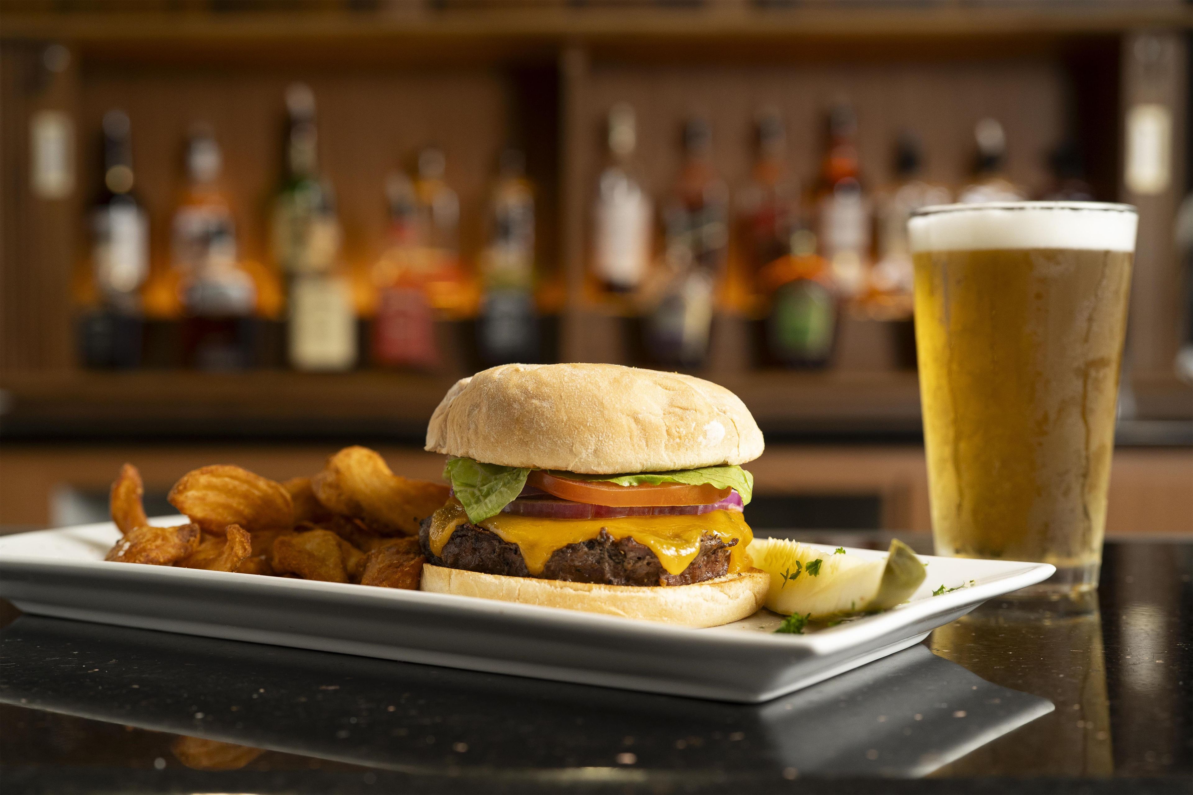 A burger with fries and a beer on a table.