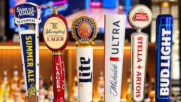 A row of beer taps with labels such as Samuel Adams, Yuengling, Miller Lite, Michelob, Stella Artois, and Bud Light.