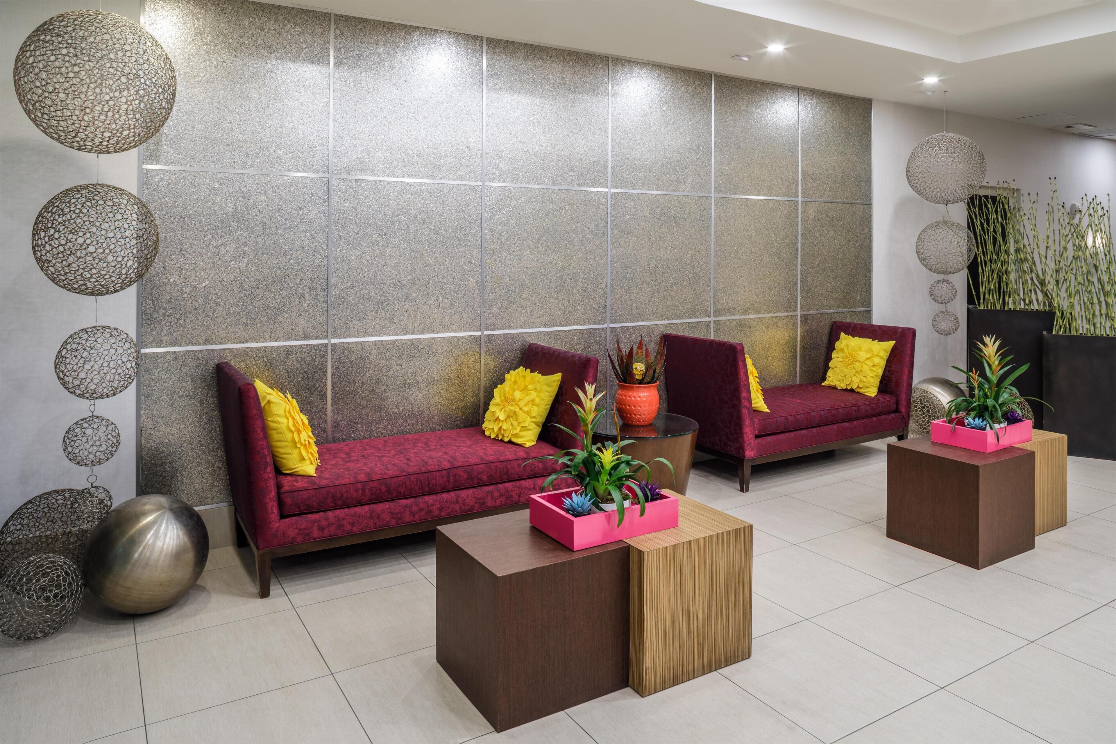 Eine moderne Lobby mit zwei Sofas, einem Couchtisch, dekorativen Kugeln und einer Topfpflanze.
