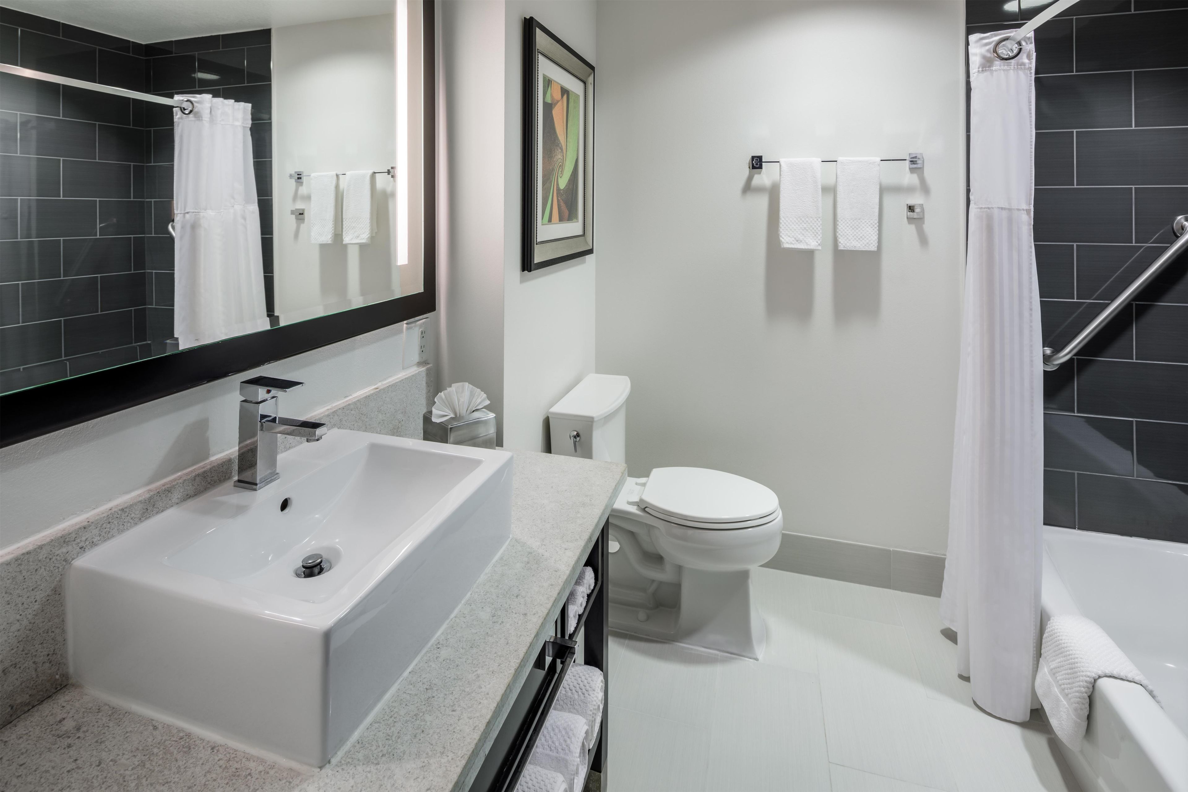 A modern bathroom with a white sink, toilet, and bathtub.