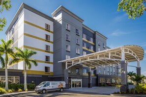 A multi-story hotel with a covered entrance, palm trees, and a van parked outside. - DoubleTree by Hilton Sarasota Bradenton Airport (Sarasota)