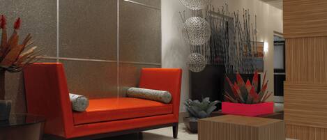 A modern living room with a red sofa, a glass coffee table, and decorative plants.