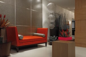 Una sala moderna con un sofá rojo, una mesa de centro de vidrio y plantas decorativas.
