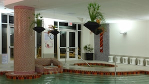 An indoor pool with a tiled wall, a clock, and a sign indicating no diving.