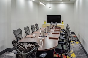 A conference room with a long table, chairs, a flat-screen TV, and two yellow vases with flowers. - DoubleTree by Hilton Sarasota Bradenton Airport (Sarasota)