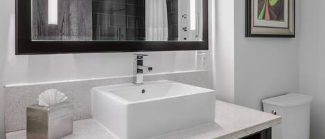 A bathroom with a white sink, dark vanity, and a large mirror.