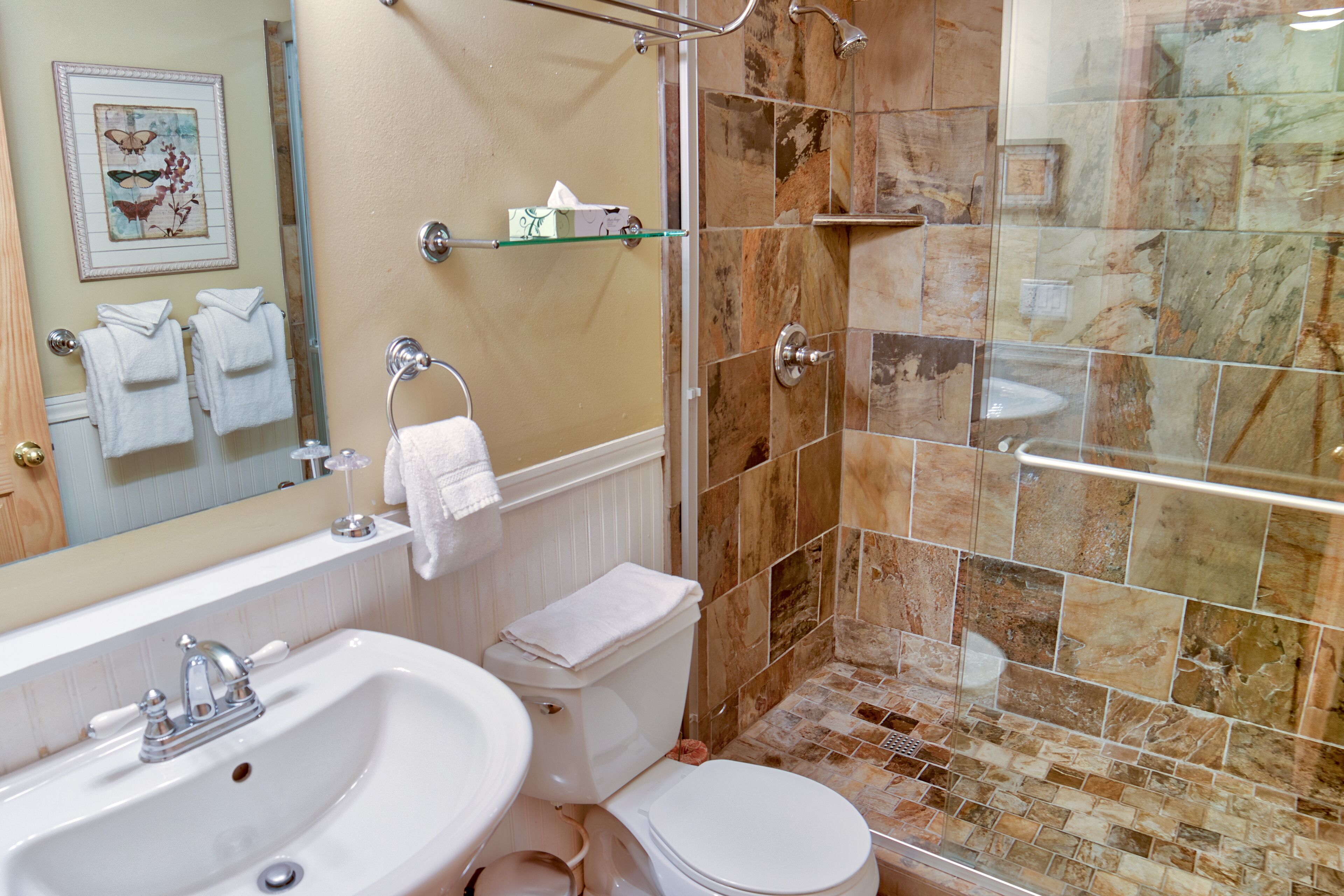 A bathroom with a sink, toilet, and shower area.