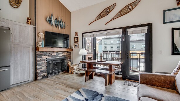 A living room with a fireplace, a television, a dining area, and a sofa. - Der Steiermark (Breckenridge)