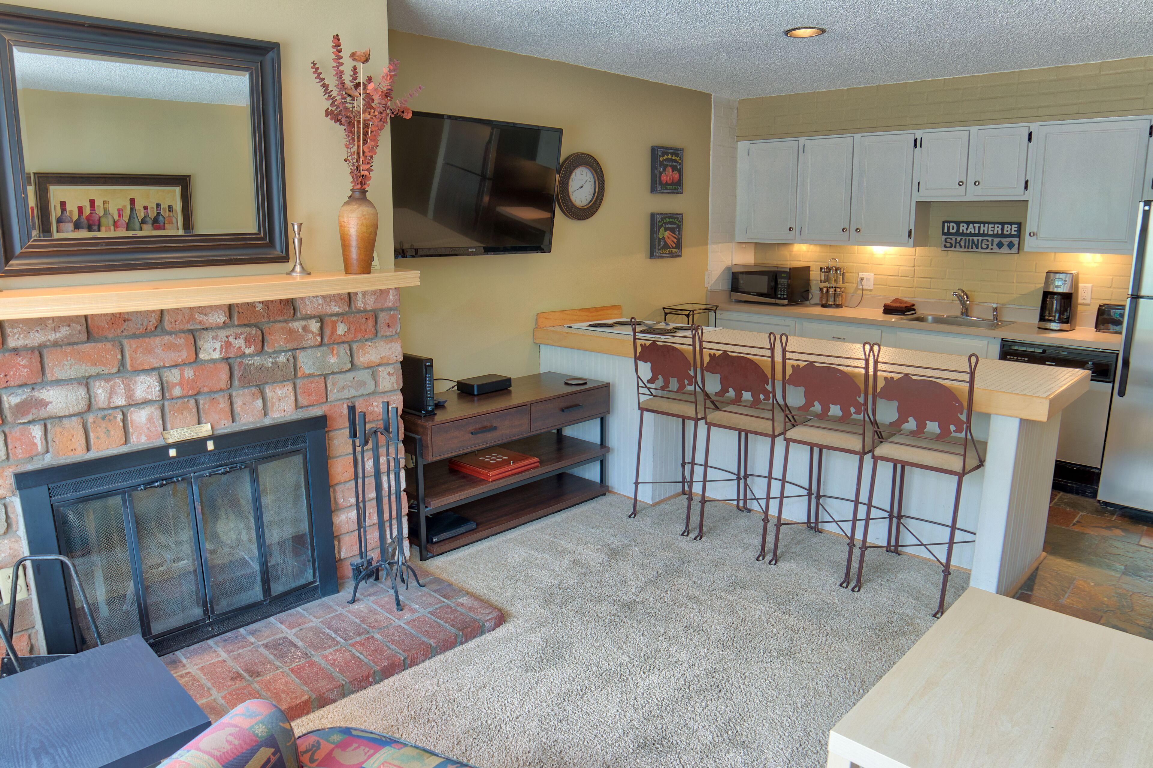 Una cocina con chimenea, televisor y zona de bar con taburetes.