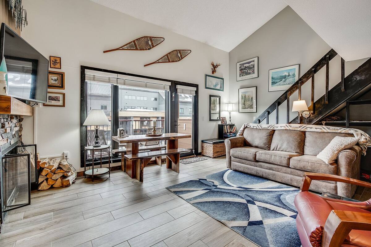 Un salon chaleureux avec un plancher en bois, un canapé, une table basse et un escalier.