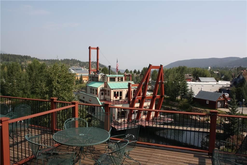 Una terrazza con sedie e tavolo in metallo, affacciata su un ponte e degli edifici.