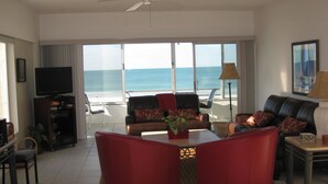 Un salón con vista al océano, un televisor y una mesa con una planta.