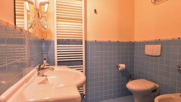 Un bagno con lavandino, wc e porta asciugamani.