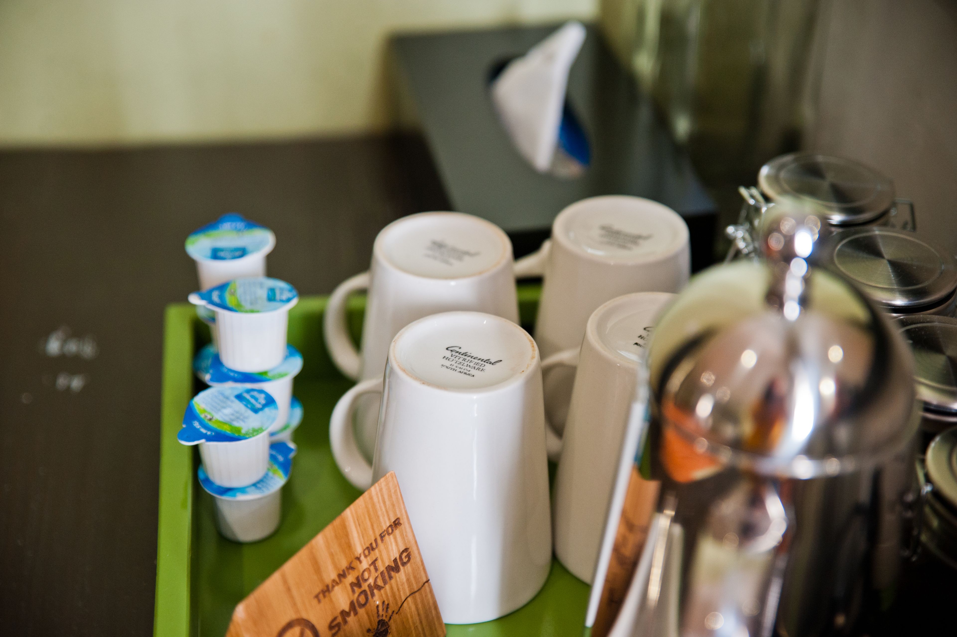 A tray with several white mugs and a stainless steel coffee pot.