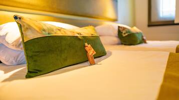 A hotel room with two beds, each with green pillows and a small decorative item on the pillows.