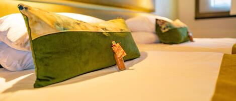 A hotel room with two beds, each with green pillows and a small decorative item on the pillows.