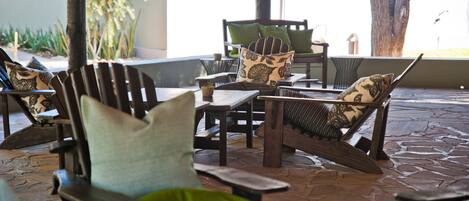 A patio area with wooden furniture and green cushions.