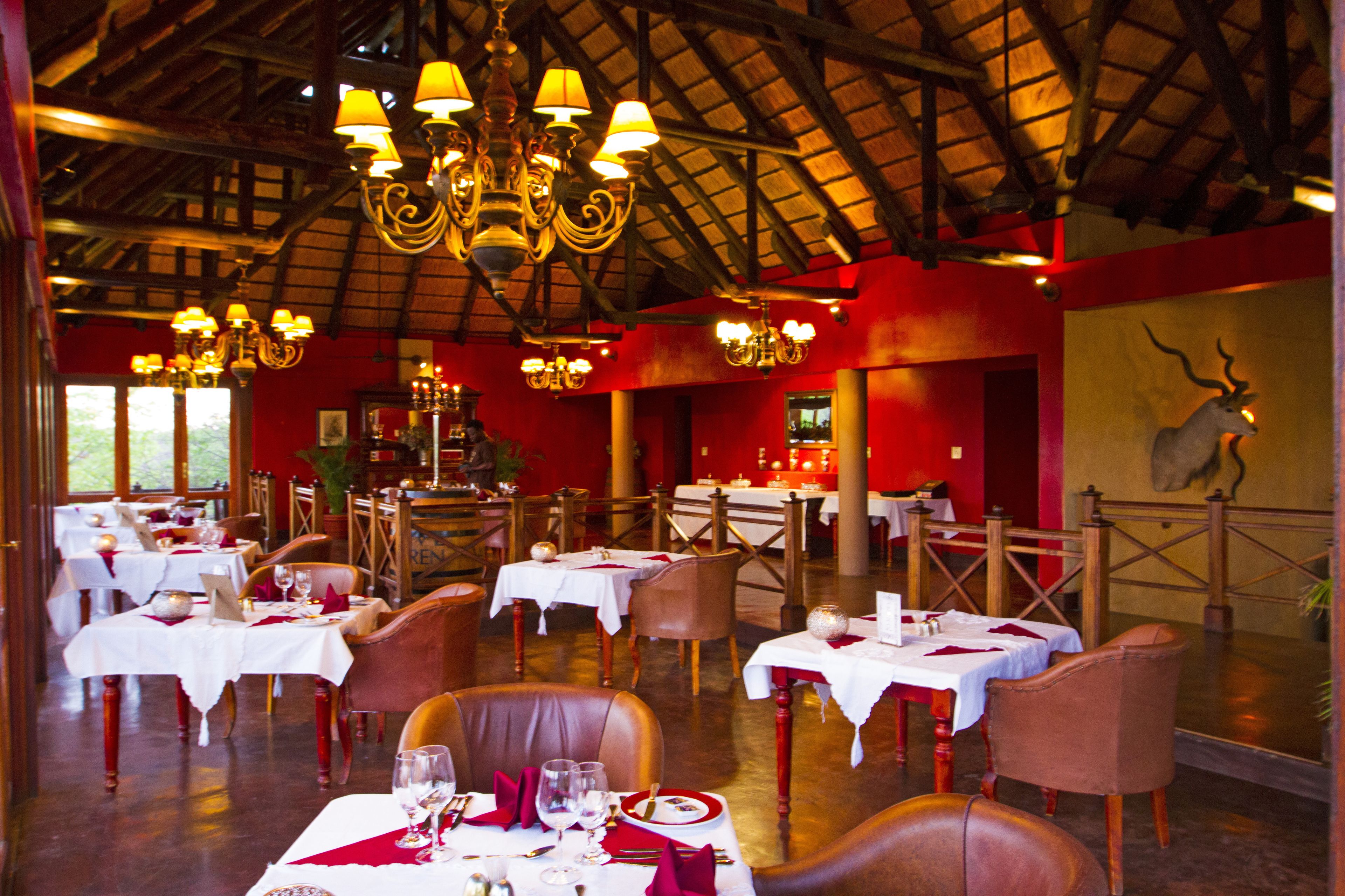 A restaurant with tables set for dining, wooden chairs, and chandeliers.