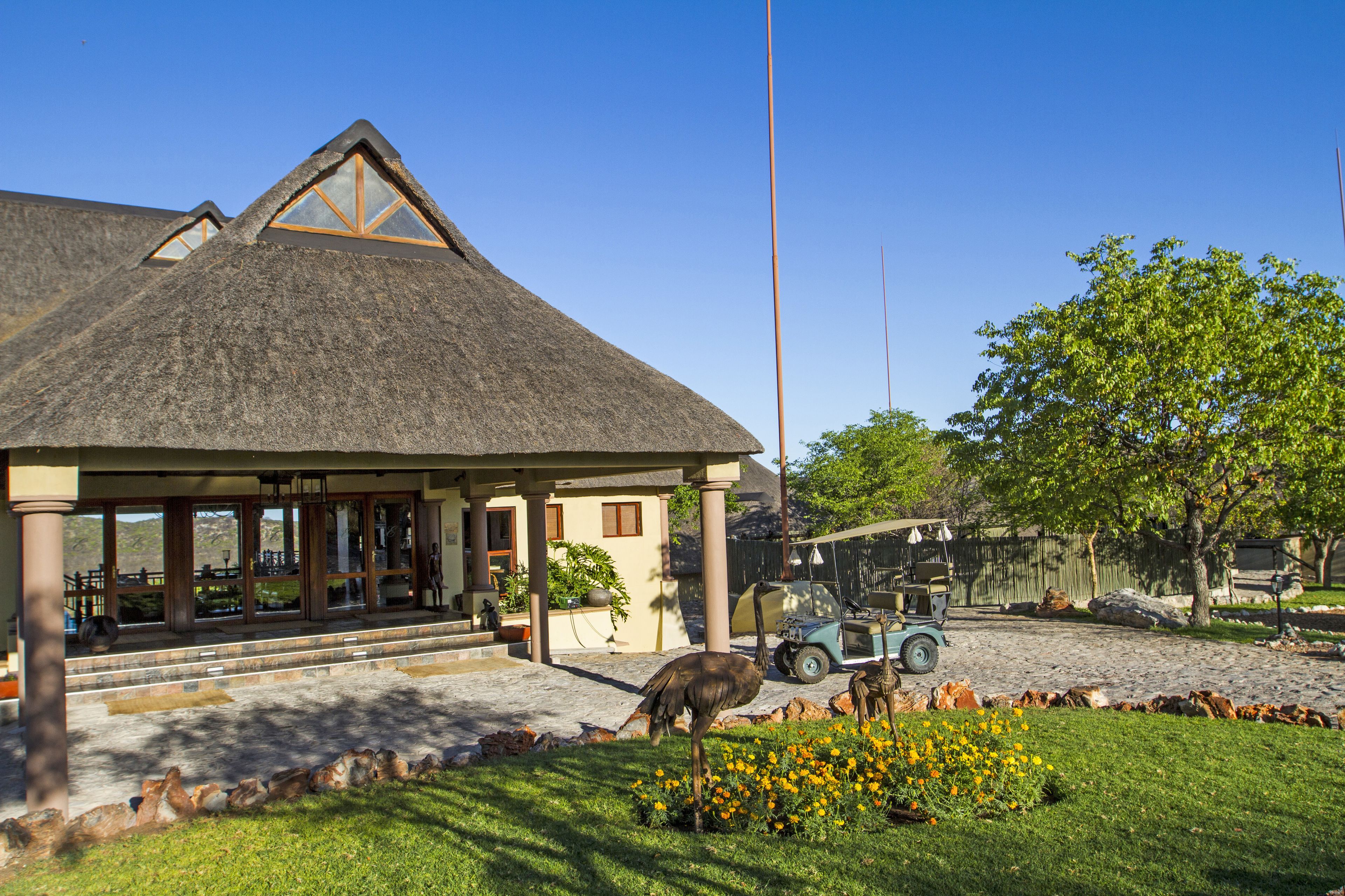 A building with a thatched roof, a covered entrance, and a paved driveway.