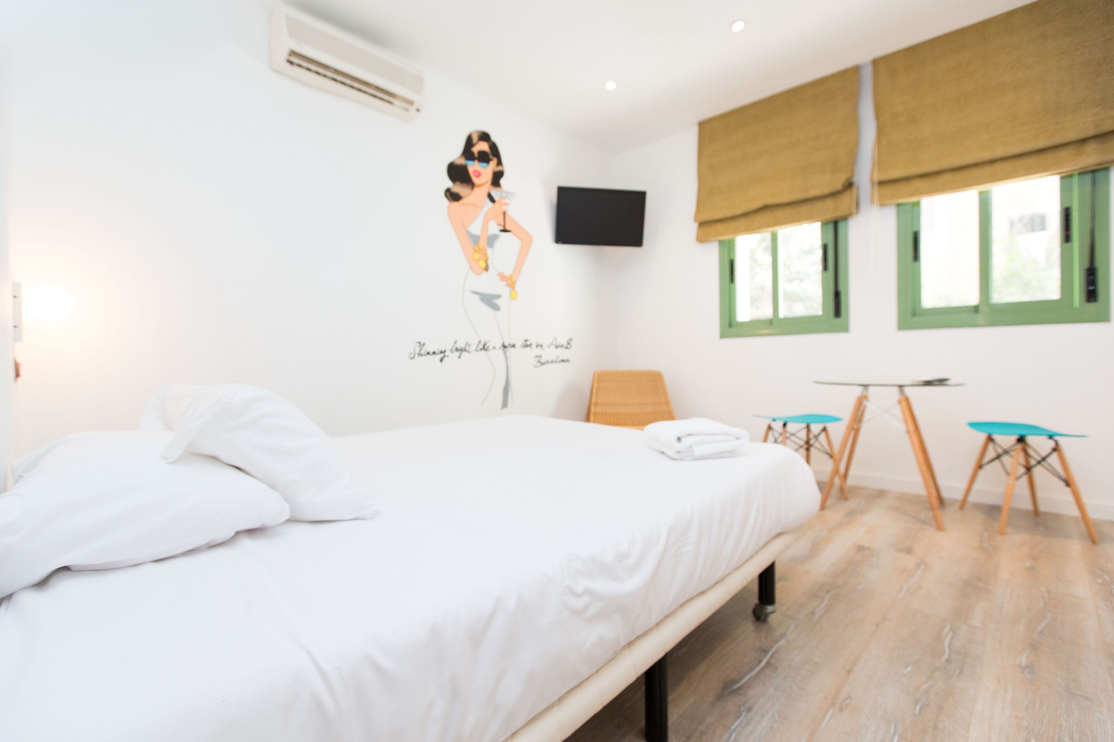Hotelkamer met een bed, een wandtelevisie, een raam met uitzicht en een kleine tafel met stoelen.