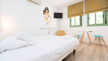 Hotelkamer met een bed, een wandtelevisie, een raam met uitzicht en een kleine tafel met stoelen.
