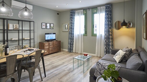 A modern living room with a dining area, a sofa, a coffee table, and a TV. - AinB Las Ramblas Colón Apartments (Barcelona)