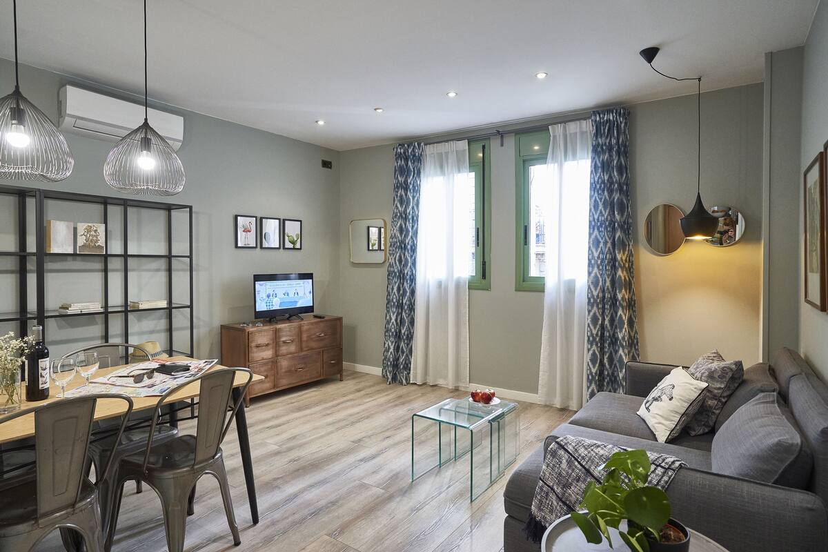 Uma sala de estar moderna com área de jantar, sofá, mesa de centro e TV.