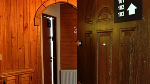 Pasillo interior de madera con un cartel que indica los números de habitación 101, 102 y 103.