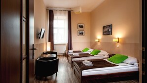 Habitación de hotel con tres camas, un escritorio y una silla.