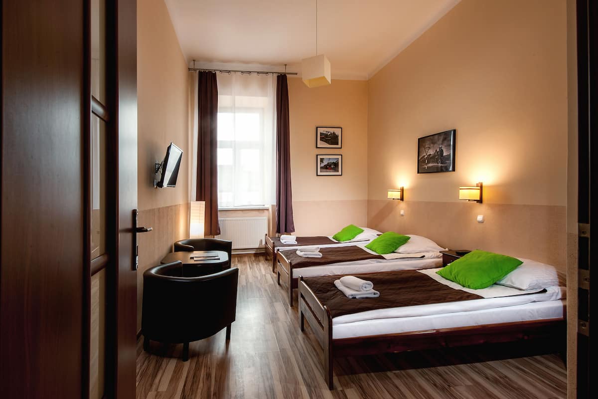 Une chambre d’hôtel avec trois lits, un bureau et une chaise.
