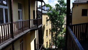 Un edificio de varios pisos con balcones y un árbol en primer plano.