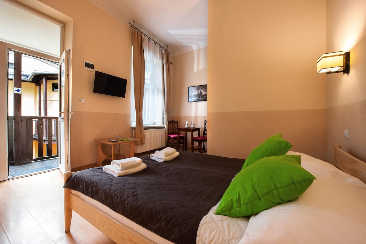 Une chambre d’hôtel équipée d’un lit, d’un bureau, d’une chaise, d’une télévision et offrant une vue sur l’extérieur.