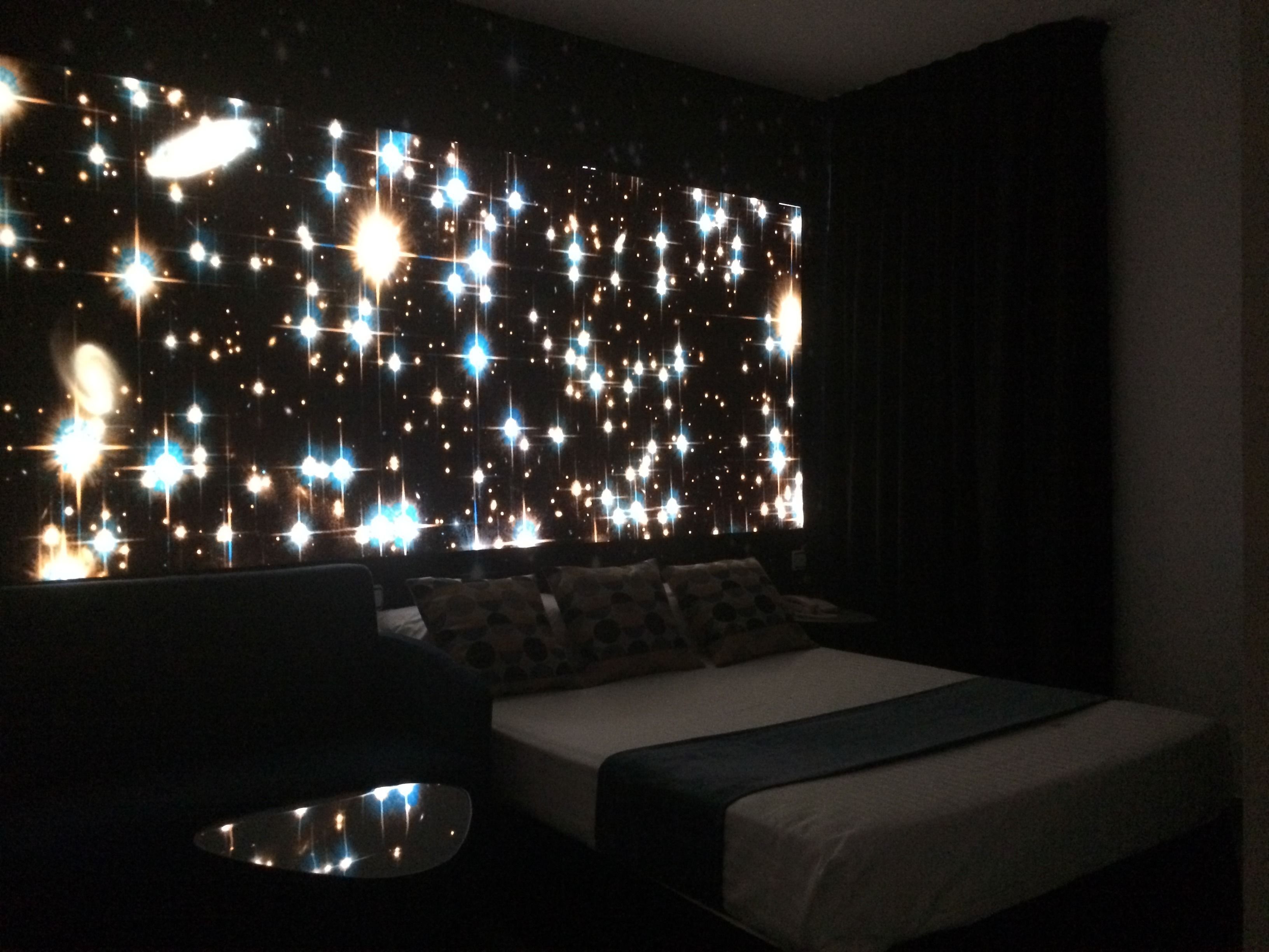 A bedroom with a bed, pillows, and a bedside table.