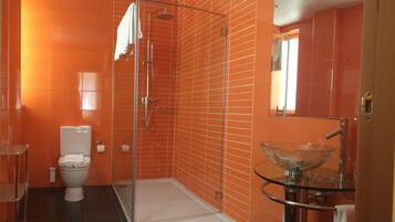 A bathroom with orange tiled walls, a glass shower enclosure, a white toilet, and a glass sink with a modern design.