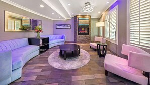 Una sala moderna con un sofá curvo, una mesa de centro redonda y un sillón rosa.