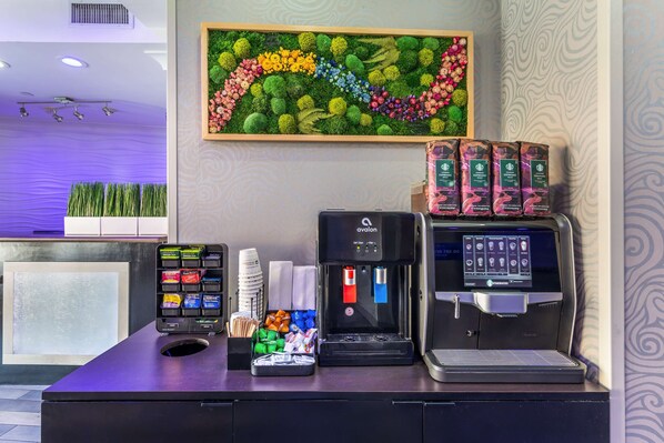 A coffee station with a coffee machine, a selection of coffee pods, and a phone charging station.