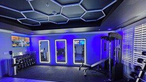 Un gimnasio con techo de diseño hexagonal, paredes espejadas y equipamiento de ejercicio.