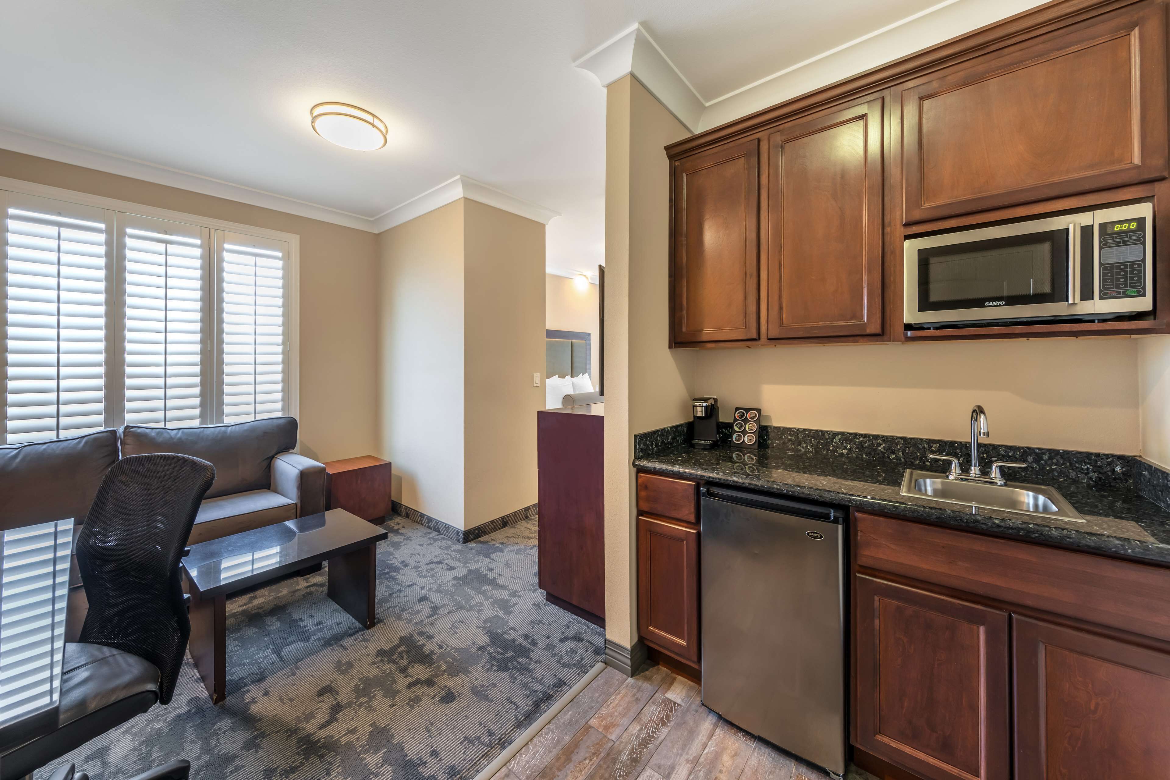 A compact kitchen with wooden cabinets, a built-in microwave, and a stainless steel dishwasher.