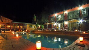 Ein Poolbereich mit Pool, Sitzgelegenheiten im Freien und einem Gebäude mit mehreren Fenstern und Balkonen.