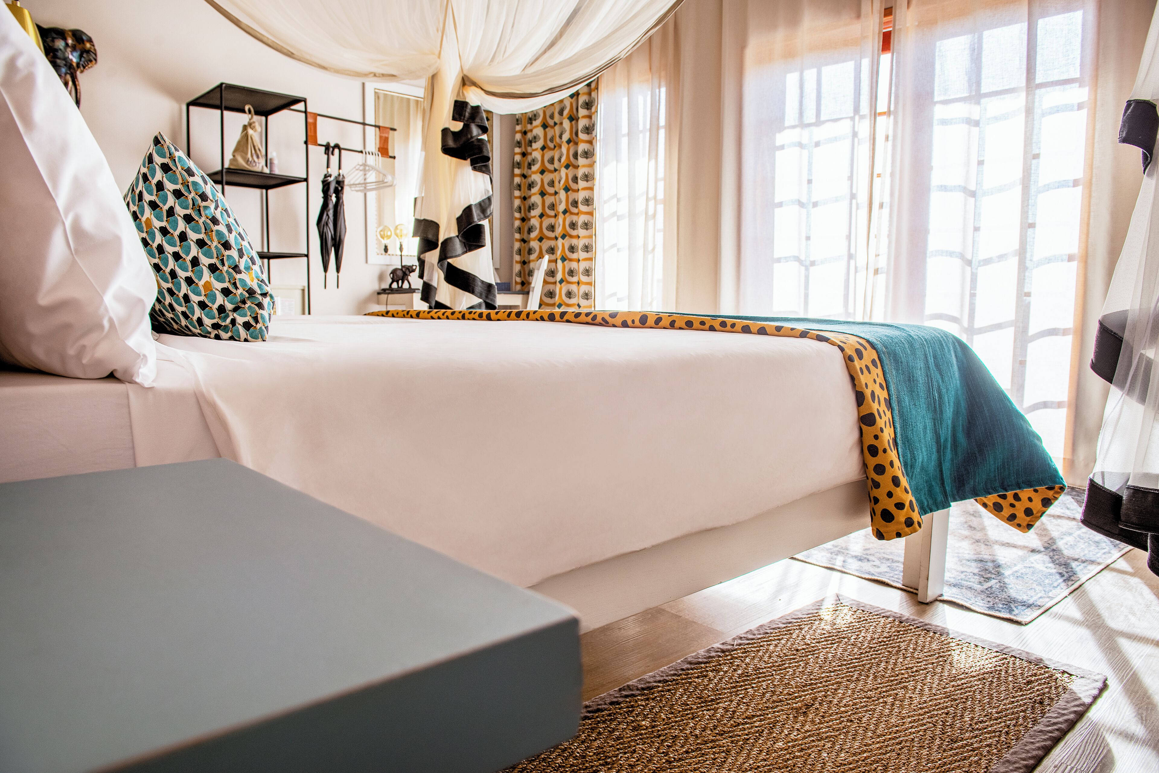 A modern bedroom with a large bed, a sofa, a small table, and a wardrobe.