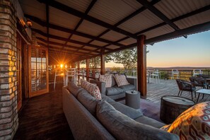 An outdoor seating area with a covered patio, wooden flooring, and a view of the landscape. - Etosha Safari Lodge (Okaukuejo)
