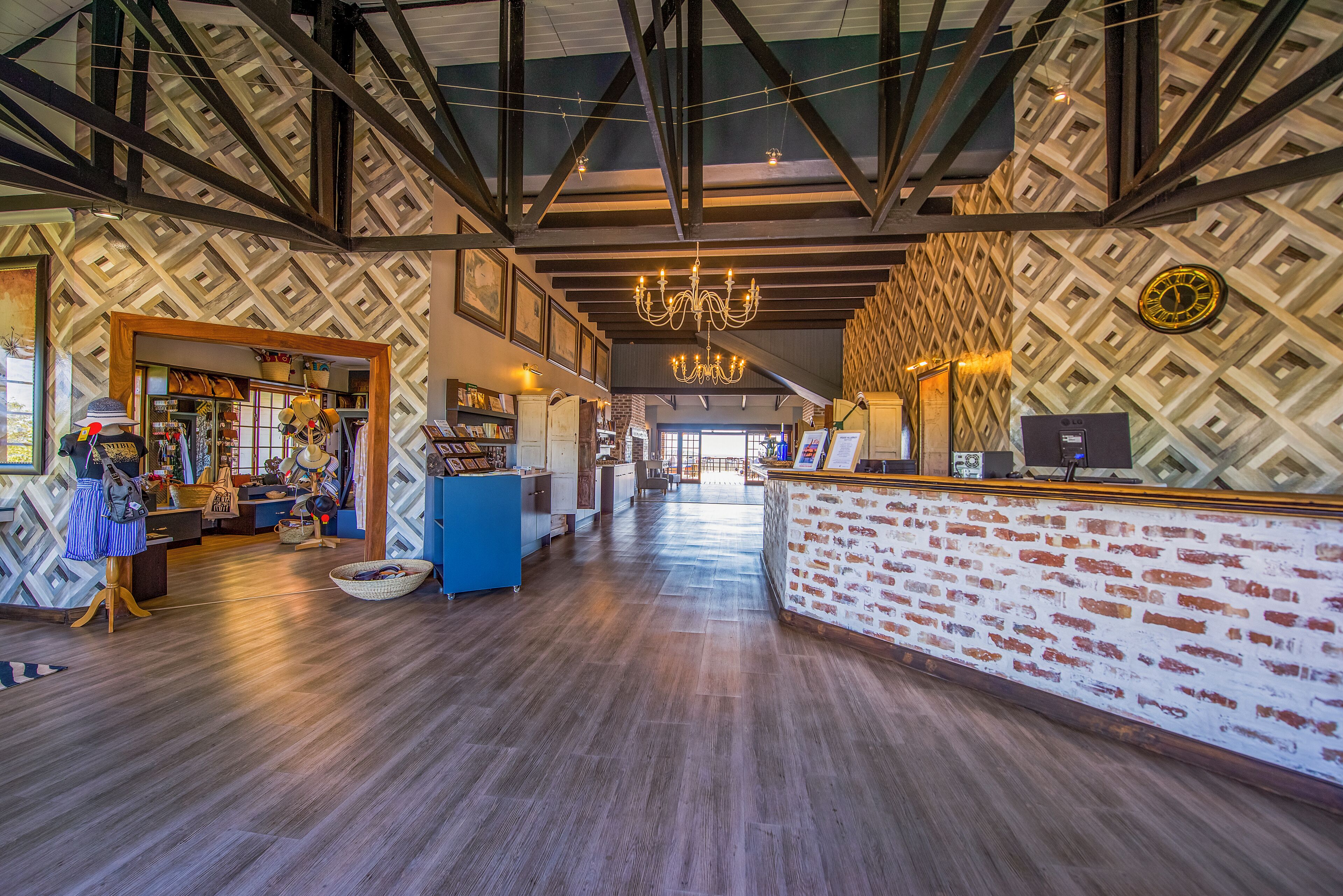 Eine großzügige Lobby mit Holzboden, einem Empfangstresen mit Backsteinfassade und einer Wand mit Musterdesign.
