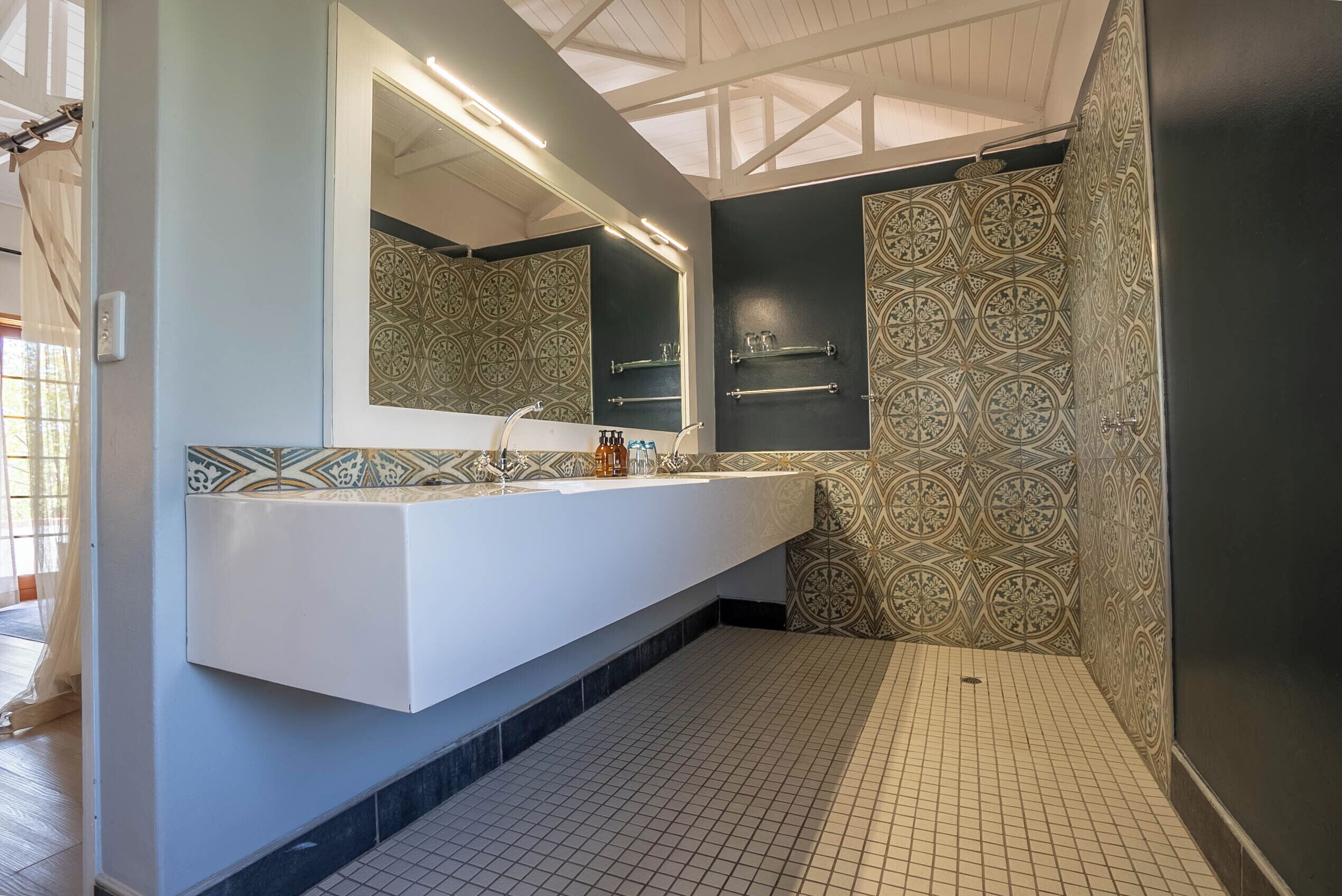 A modern bathroom with a white vanity, patterned tiles, and a large mirror.
