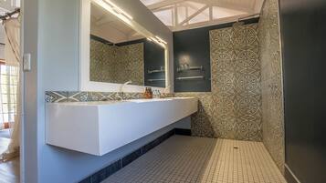 A modern bathroom with a white vanity, patterned tiles, and a large mirror.