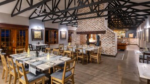 Een restaurant met bakstenen muren, houten balken en gedekte tafels.