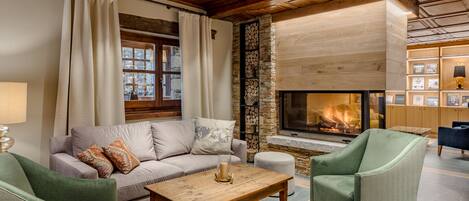 Una sala de estar acogedora con chimenea, un sofá, dos sillones y una mesita de centro.