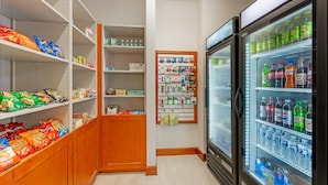 A snack and beverage section with shelves stocked with chips, bottled water, and a refrigerated display case containing sodas. - Comfort Suites French Lick (French Lick)