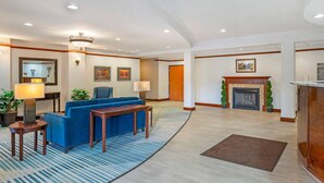 A spacious lobby with a blue sofa, a wooden table, and a fireplace. - Comfort Suites French Lick (French Lick)
