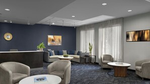 Eine moderne Hotelhalle mit Empfangstresen, einer Lounge und großen Fenstern.