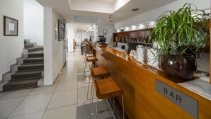 Eine Bar mit Holztresen, Barhocker und einer Zimmerpflanze.